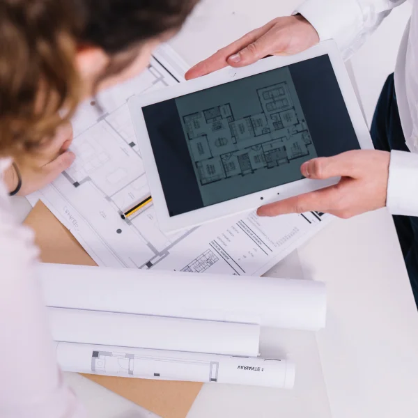 Un homme et une femme regardent un ordinateur tablette, discutant de la gestion de projet.