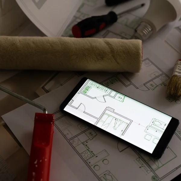 Smartphone affichant des plans de rénovation avec des outils, symbolisant les étapes d'une rénovation réussie.