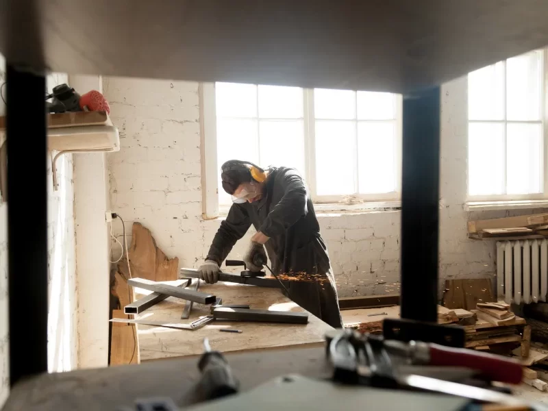 Un homme utilise une scie sur table dans une pièce, illustrant les étapes d'une rénovation réussie.