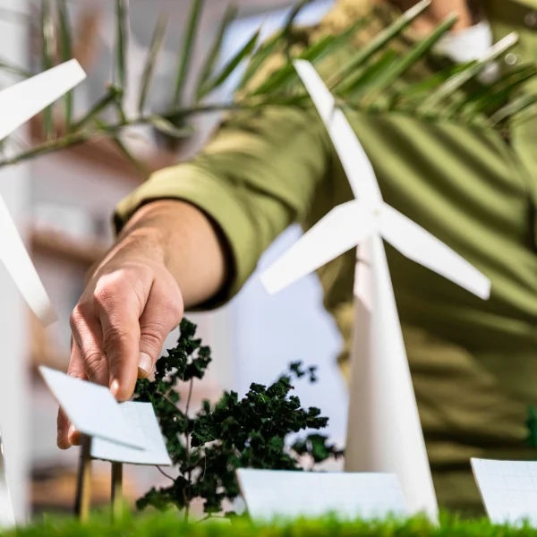 Une personne tient une pancarte avec des éoliennes, illustrant un projet de gestion de l'énergie renouvelable.