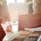 Un homme et une femme se tiennent devant un bureau avec des échantillons de bois pour une rénovation écologique.