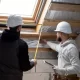 eux hommes en casques mesurent le toit d'une maison, évaluant les matériaux nécessaires pour le projet.